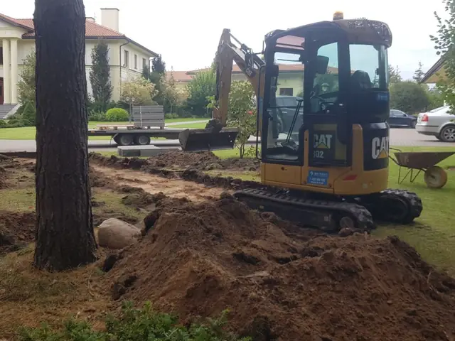 Minikoparka przygotowuje teren pod ścieżkę między sosnami