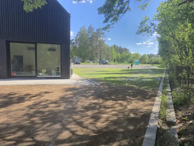 Pas wzdłuż budynku przygotowany pod trawnik, z obrzeżem przy lesie
