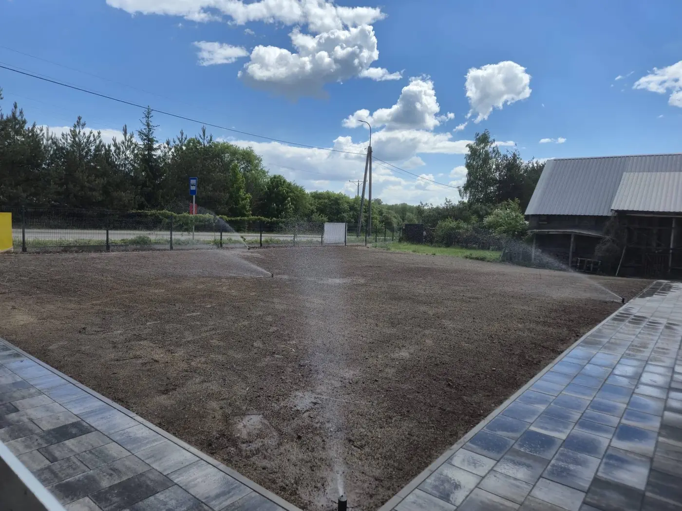 Zraszacz podlewa przygotowany trawnik przy nawierzchni z kostki